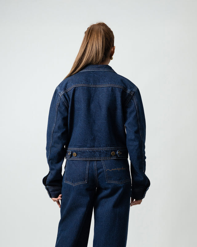 Person wearing a blue denim jumpsuit on a white background